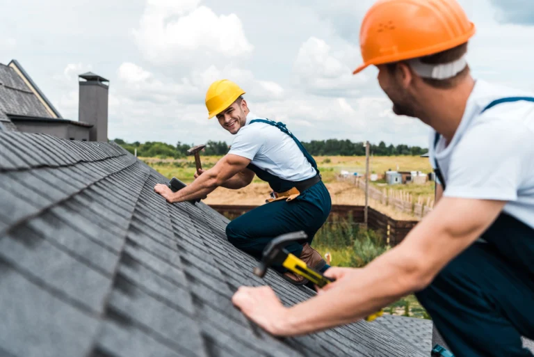 Two roofers smiling while working on the roof.